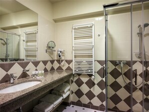 A bathroom with a granite sink, a mirror, a towel rack, a shower, and a toilet.