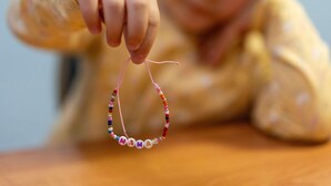 Ein Kind hält ein Armband mit der Aufschrift 'MAMA'.
