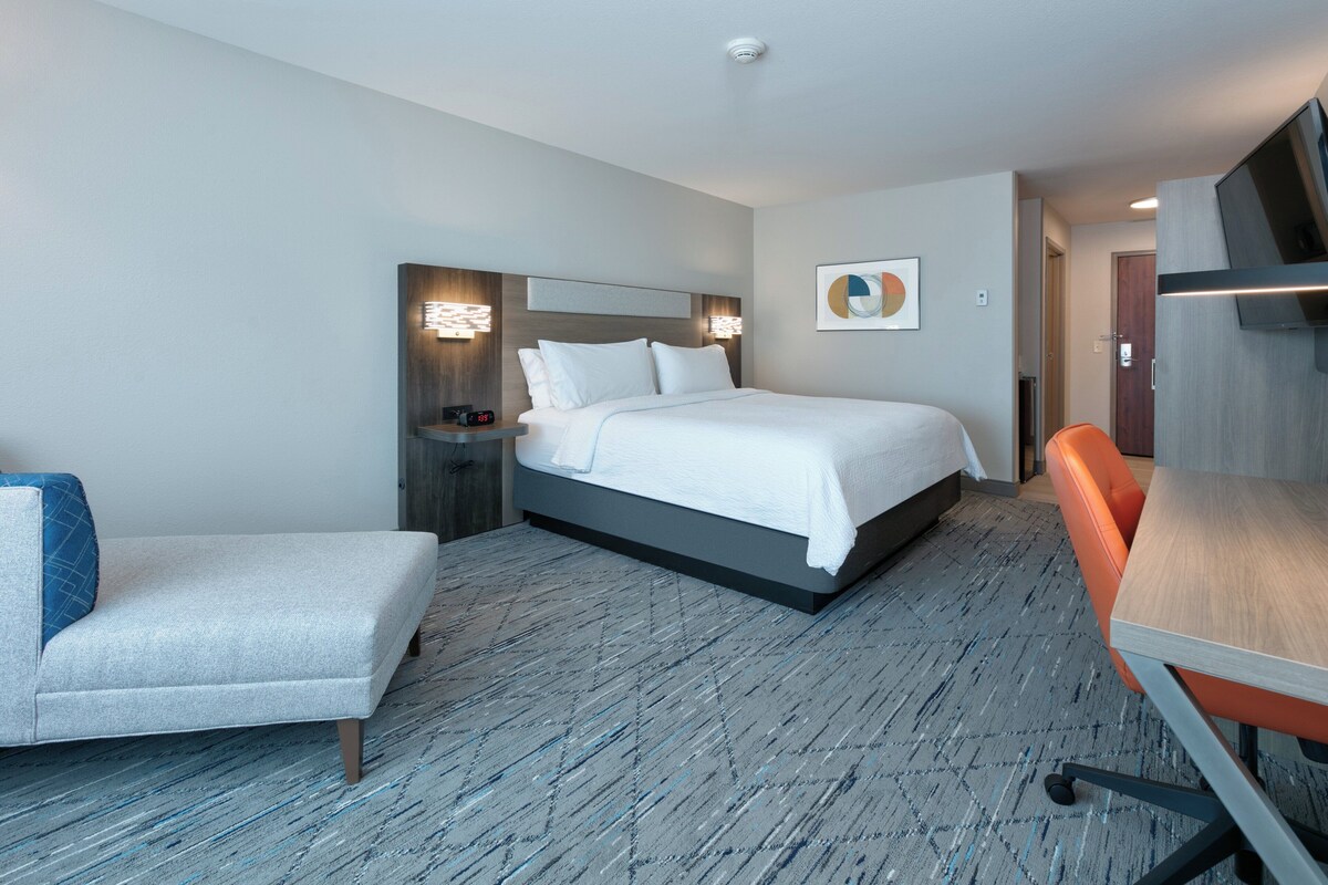 Een hotelkamer met een bed, een stoel, een bureau en een televisie.