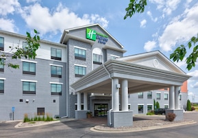A Holiday Inn Express & Suites building with a covered entrance, multiple windows, and a parking area.