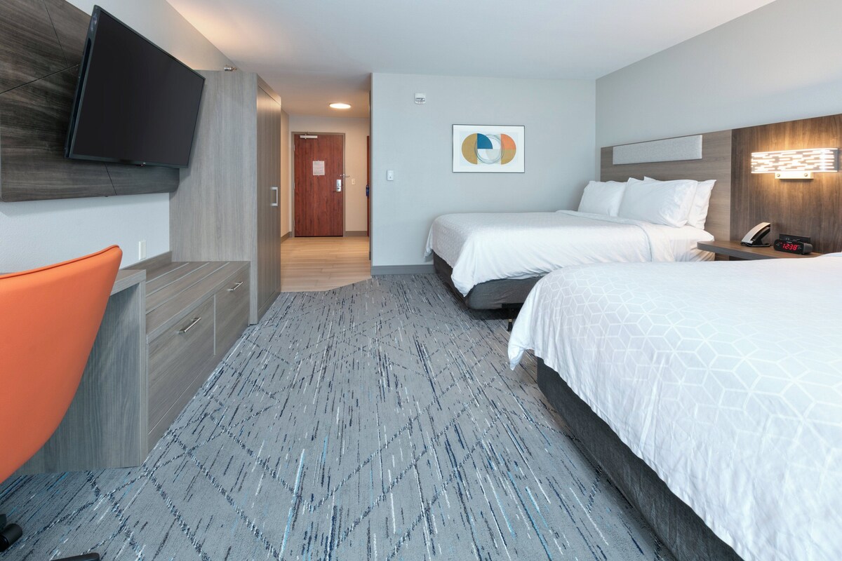 Een hotelkamer met een bed, een bureau, een stoel, een televisie en een schilderij aan de muur.