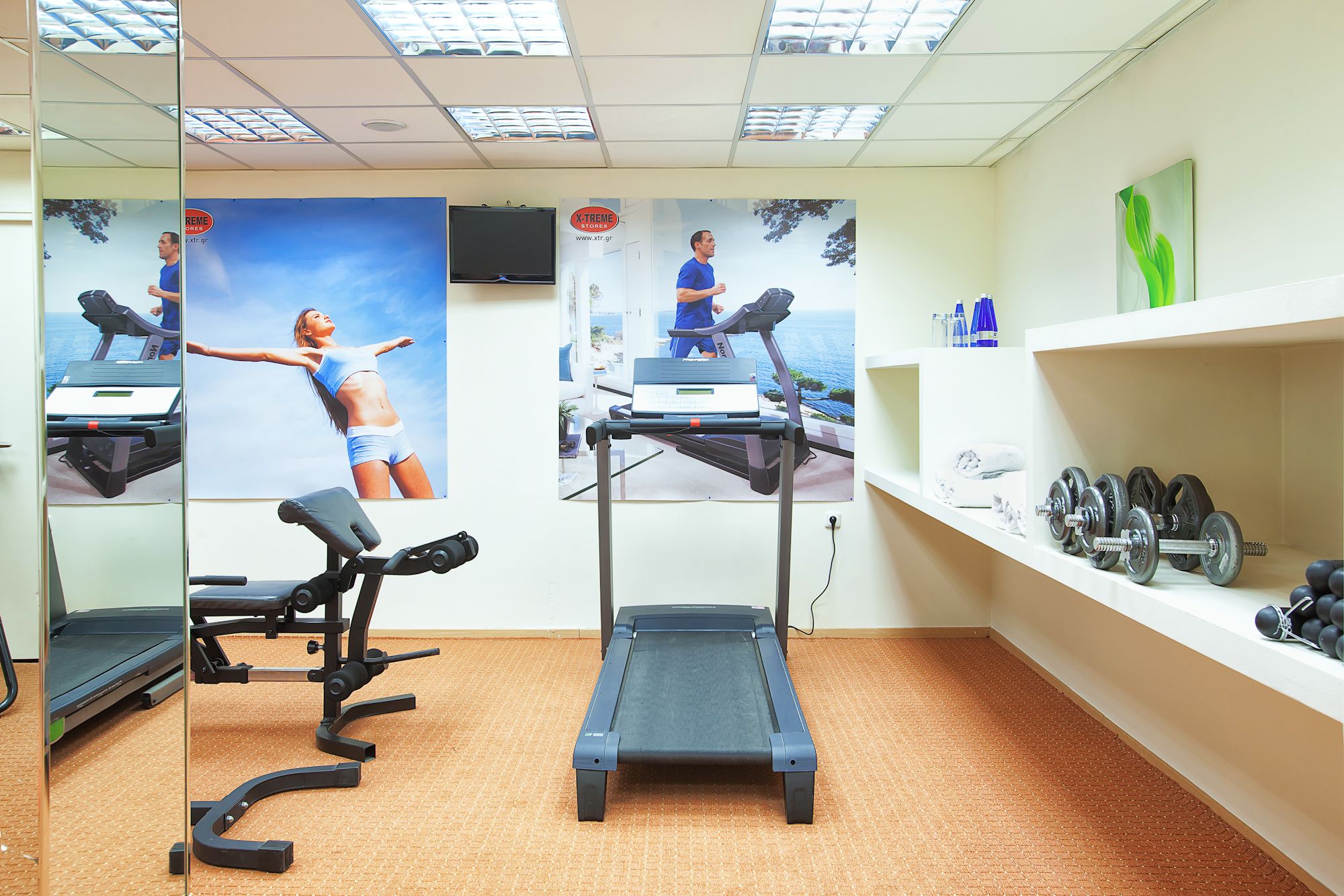 Une salle de sport équipée de tapis de course, d’un vélo d’appartement et de matériel de musculation.