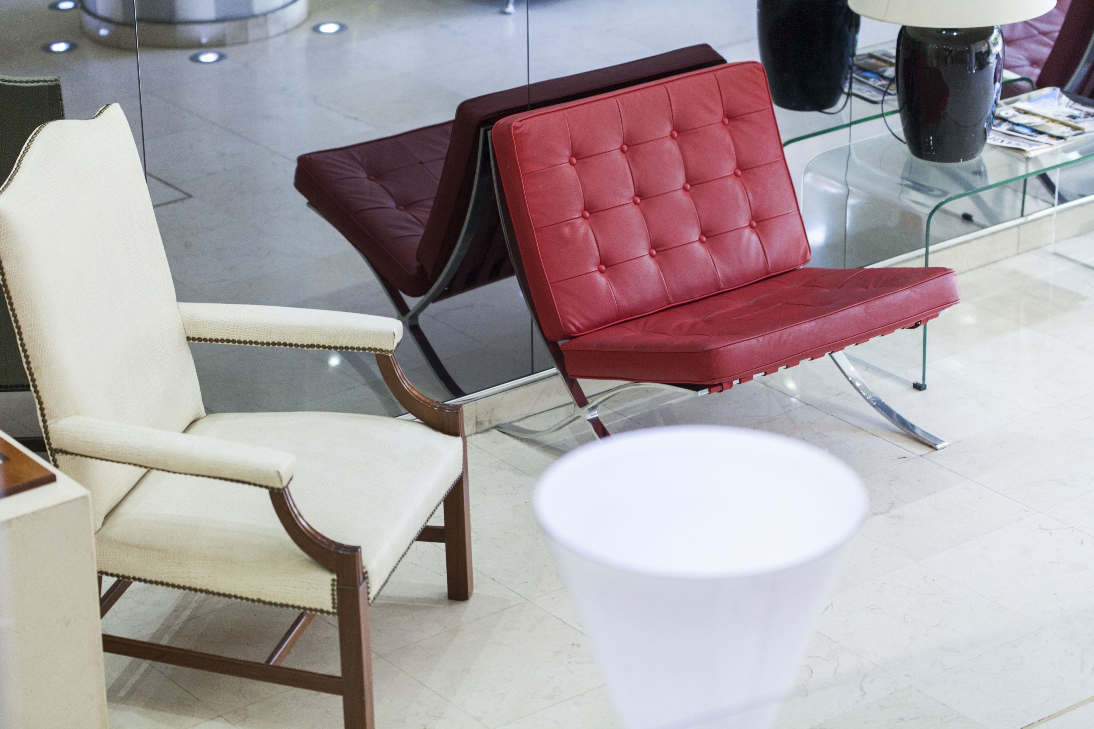 A modern interior with two chairs, one red and one white, and a white table with a lamp.