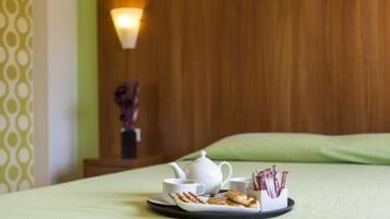 A neatly arranged breakfast tray on a bed with a teapot, cups, and pastries.