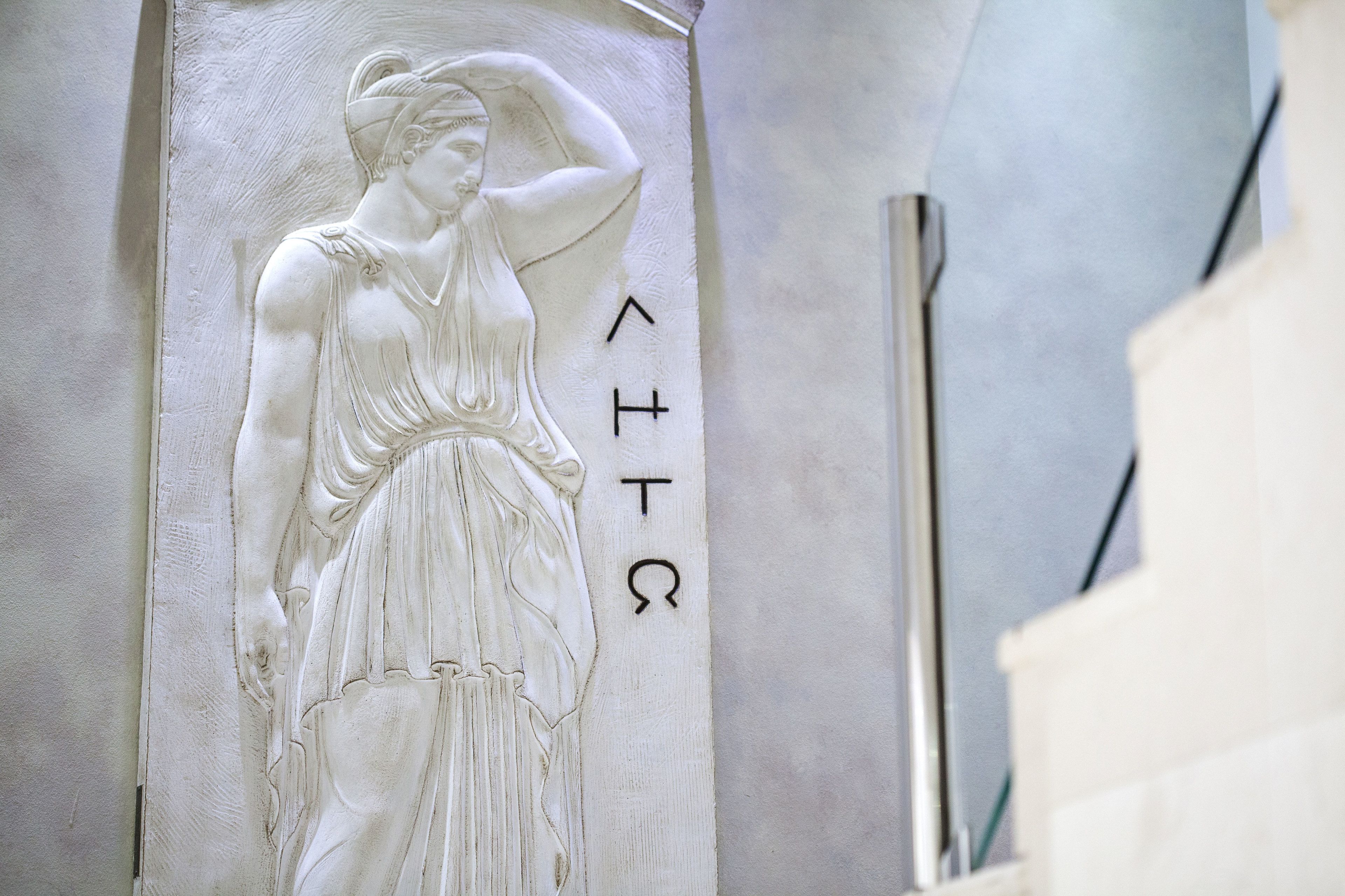 A marble relief sculpture of a woman with a headdress, inscribed with Greek letters.