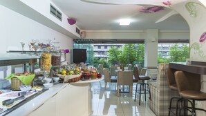 A modern dining area with a buffet setup, seating arrangements, and a view of the outdoors. - Leto Boutique Hotel (Agrinio)
