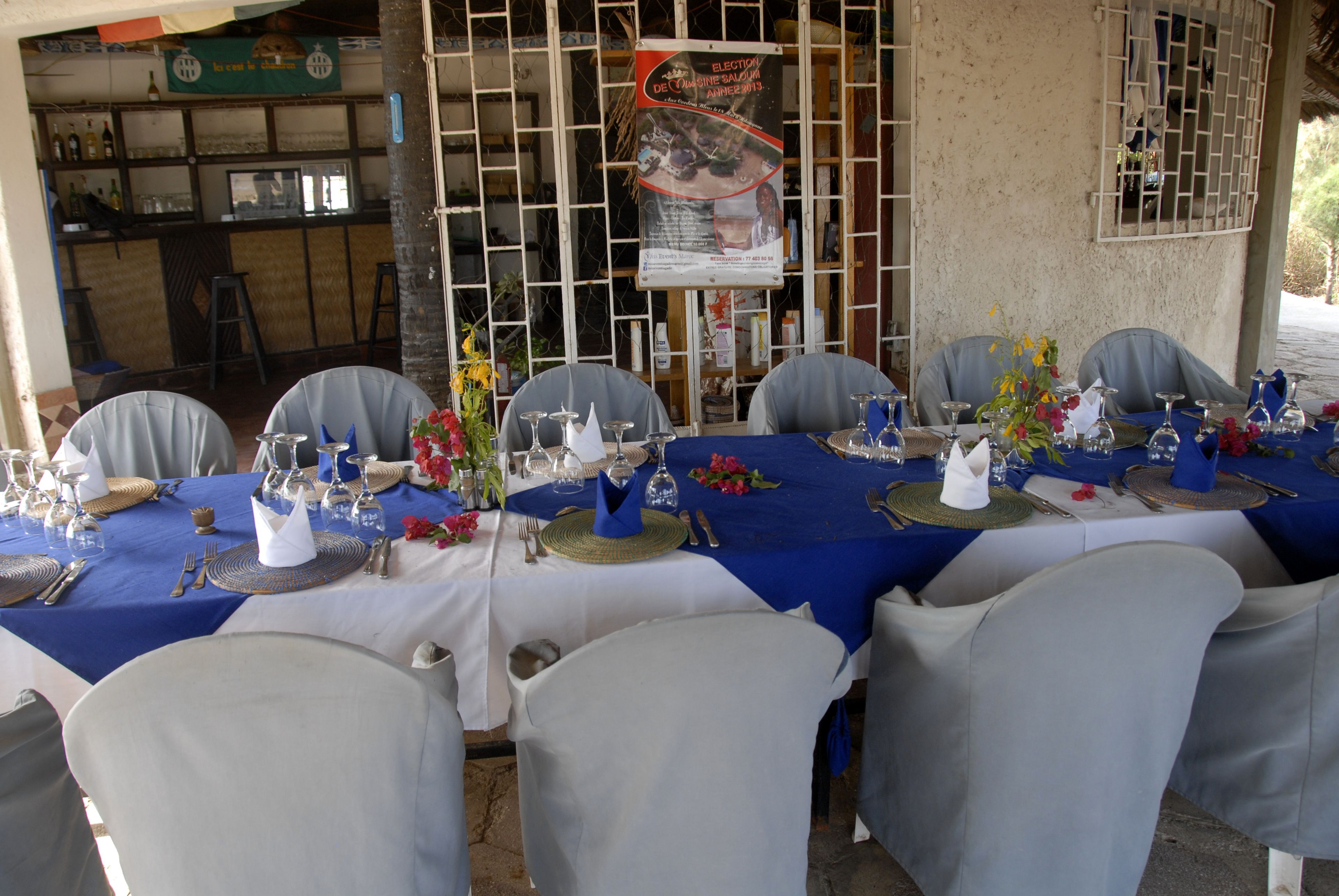 Un espace repas avec des tables dressées pour le service, des chaises et un bar en arrière-plan.