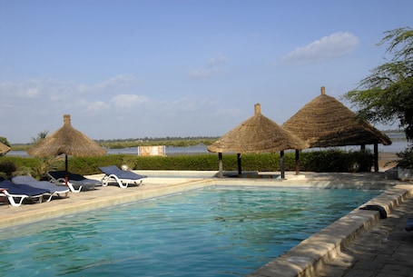 Una piscina al aire libre, sombrillas, sillones reclinables de piscina