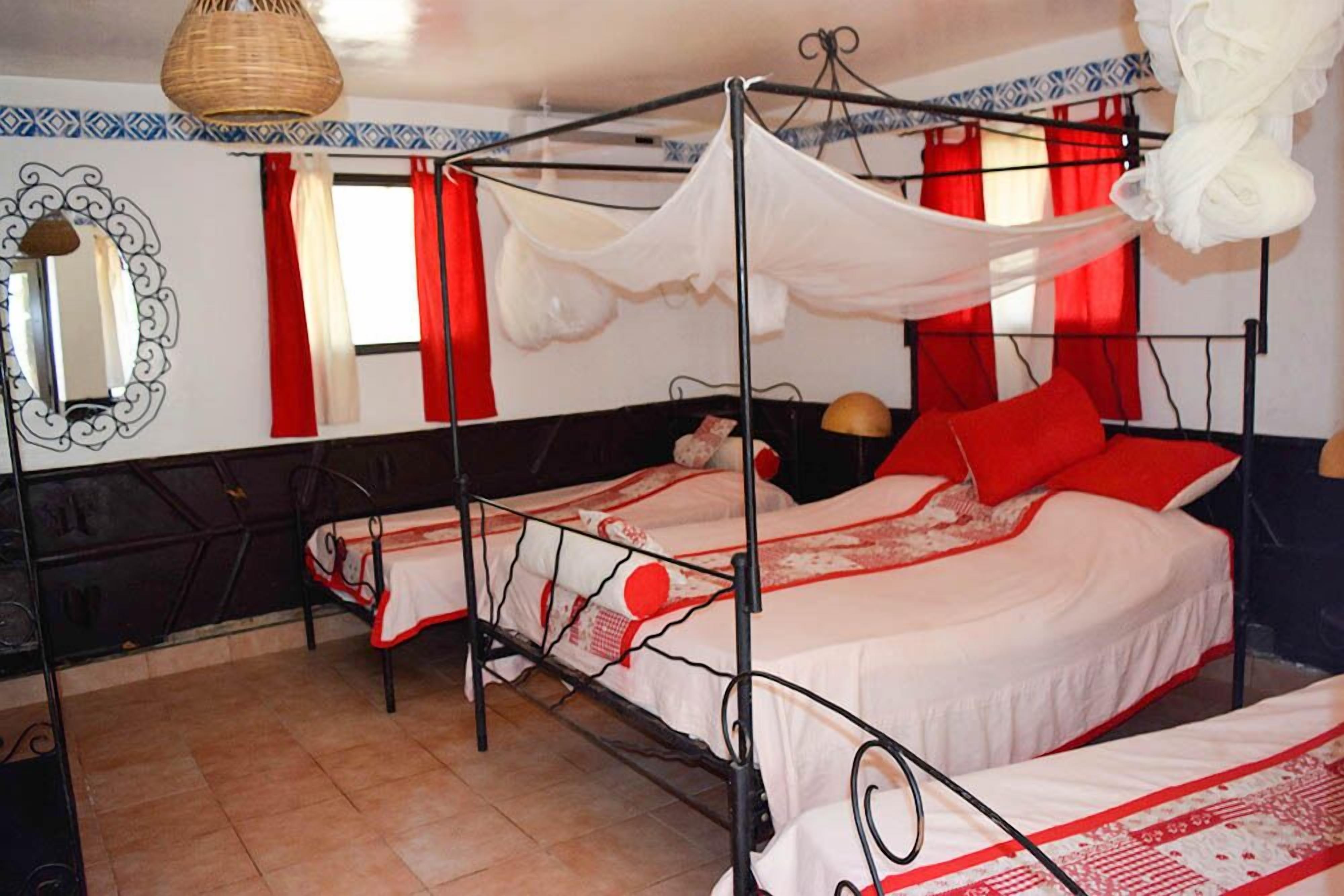 Una habitación con dos camas, un sillón colgante y un espejo en la pared.