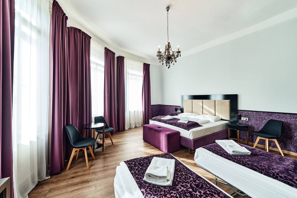 Habitación de hotel con dos camas, un escritorio, una silla y una araña.