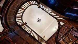 A grand, circular staircase with wooden railings and a central chandelier. - Hotel Pension Baron am Schottentor (Vienna)