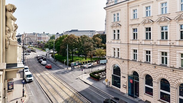 A street view with a prominent building featuring large windows and a corner entrance. - Hotel Pension Baron am Schottentor (Vienna)