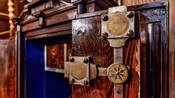 Una puerta de madera con un pestillo y una placa de latón con un emblema circular.