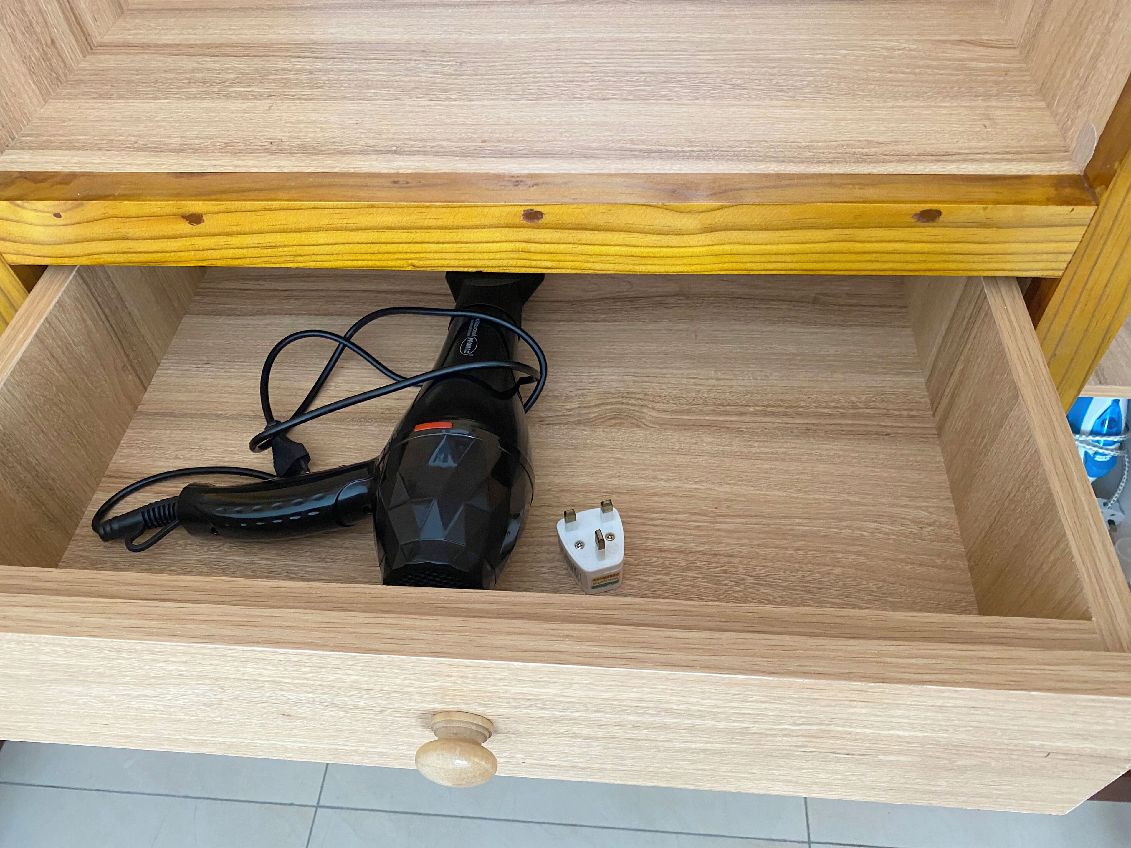 A wooden drawer with a vacuum cleaner inside.