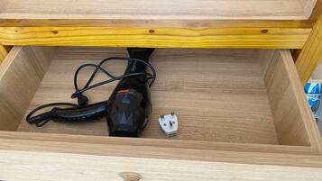 A wooden drawer with a vacuum cleaner inside.