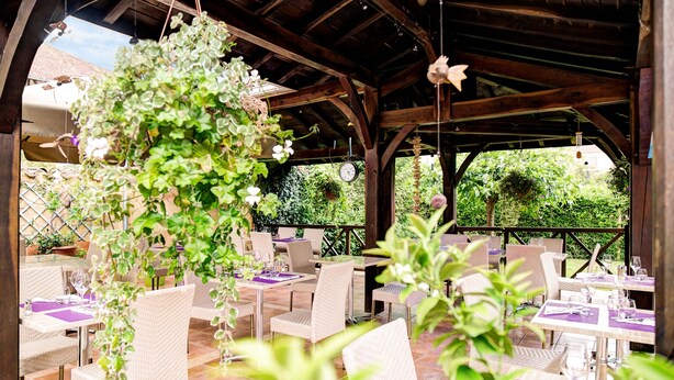 An outdoor patio with wicker chairs and tables, some with purple tablecloths. - Logis Hôtel Restaurant Du Commerce (Estang)