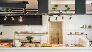 A buffet setup with various food items, a glass display case, and overhead lighting. - Potidea Golden Beach Hotel (Nea Propontida)