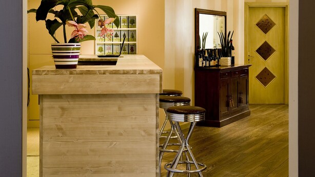 A reception area with a wooden reception desk, a potted plant, a mirror, and a cabinet with decorative items. - Villa Noce - Guest House (Brescia)