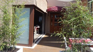 A building with a brick facade, a wooden deck, and a covered outdoor seating area. - Villa Noce - Guest House (Brescia)