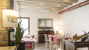 A dining area with wooden tables and chairs, a wine rack, and a mirror above the counter. - Villa Noce - Guest House (Brescia)