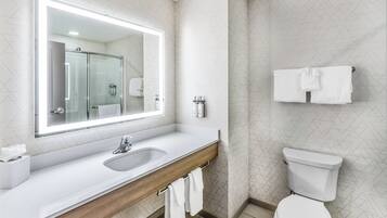 Ein modernes Badezimmer mit großem Spiegel, Waschbecken, Toilette und Handtuchhalter.