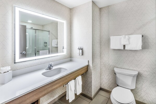 A modern bathroom with a large mirror, a sink, a toilet, and a towel rack.