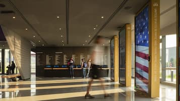 A modern indoor space with a checkered floor pattern, a wall with text and images, and a large American flag.
