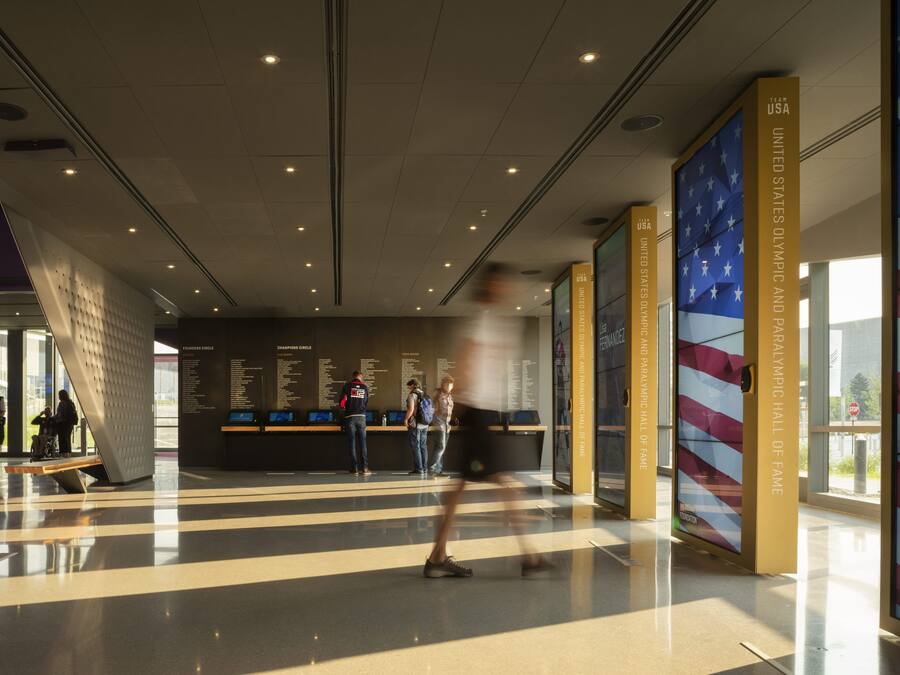 A modern indoor space with a checkered floor pattern, a wall with text and images, and a large American flag.