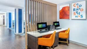 A hotel reception desk with two monitors, a wooden partition, and a framed picture of Colorado Springs. - Holiday Inn Express & Suites Colorado Springs First & Main by IHG (Colorado Springs)