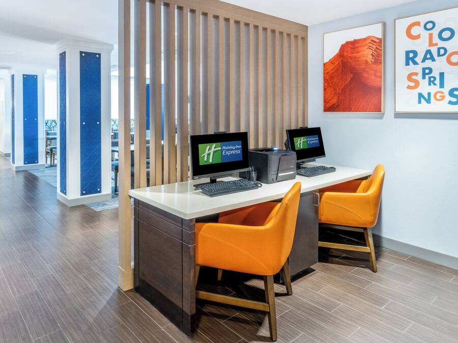 Ein Hotelrezeptionstresen mit zwei Bildschirmen, einer Holztrennwand und einem gerahmten Bild von Colorado Springs.