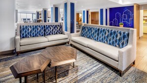 A modern hotel lobby with a sectional sofa, a wooden coffee table, and a patterned rug. - Holiday Inn Express & Suites Colorado Springs First & Main by IHG (Colorado Springs)