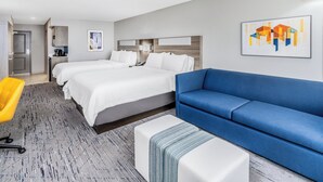 A hotel room with two beds, a blue sofa, a white ottoman, a yellow chair, and artwork on the walls. - Holiday Inn Express & Suites Colorado Springs First & Main by IHG (Colorado Springs)