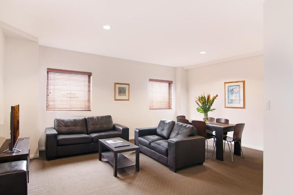 A modern living room with two sofas, a coffee table, and a dining table with chairs.