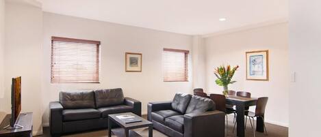 A modern living room with two sofas, a coffee table, and a dining table with chairs.