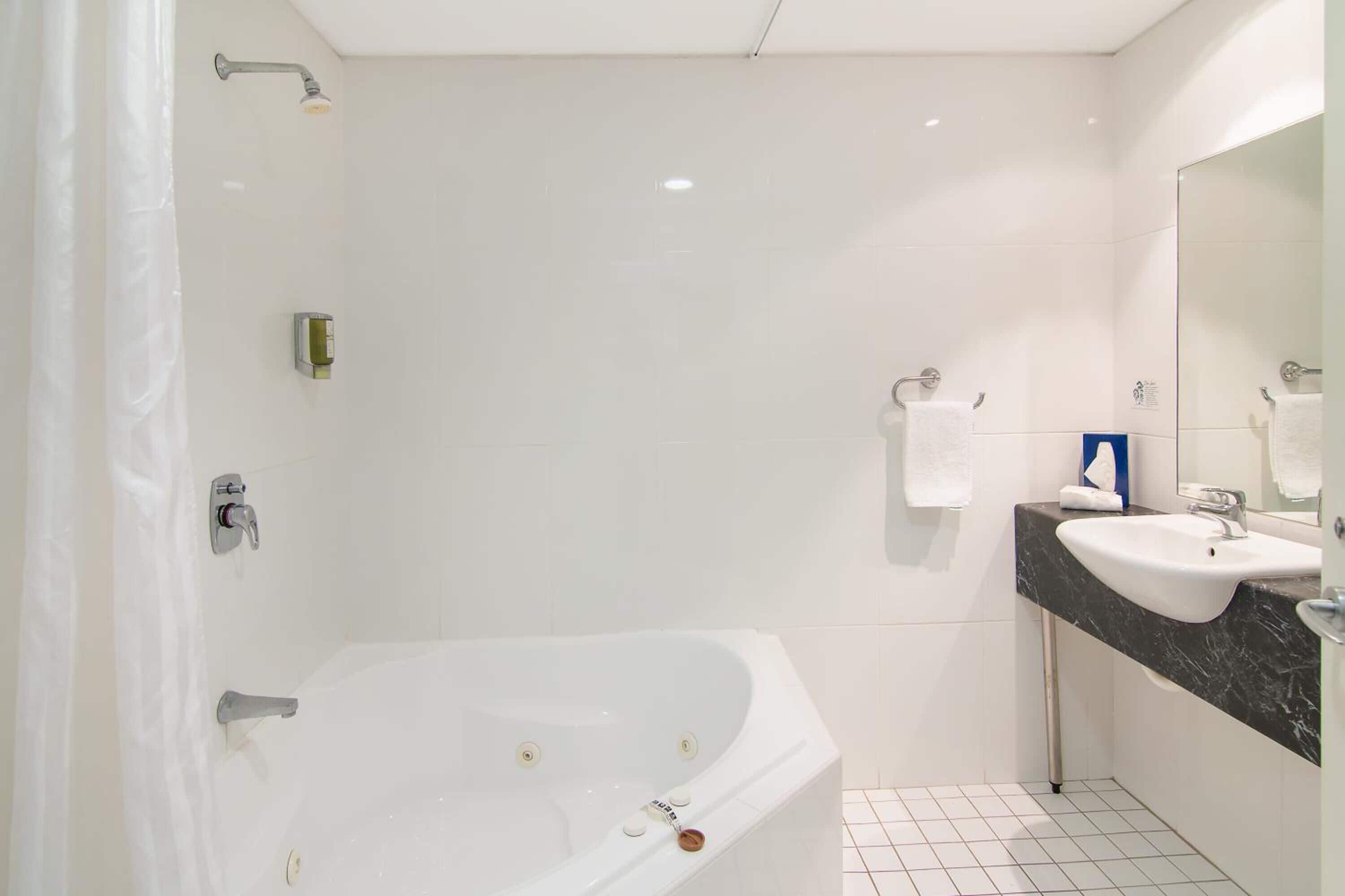 A modern bathroom with a white bathtub, a sink, and a shower.