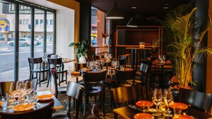 A restaurant interior with tables set for dining, chairs, and potted plants. - Boulevard on Beaumont (Hamilton)