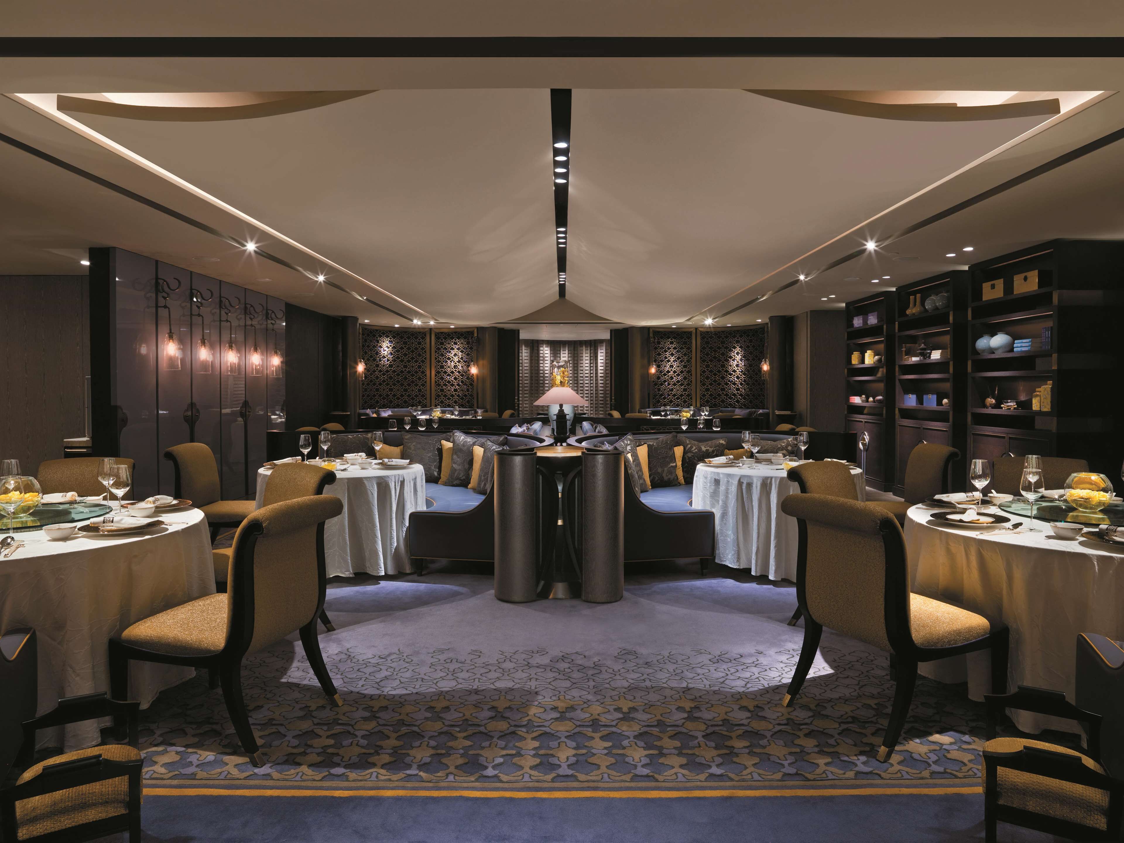 A modern dining area with round tables, chairs, and a central bar.