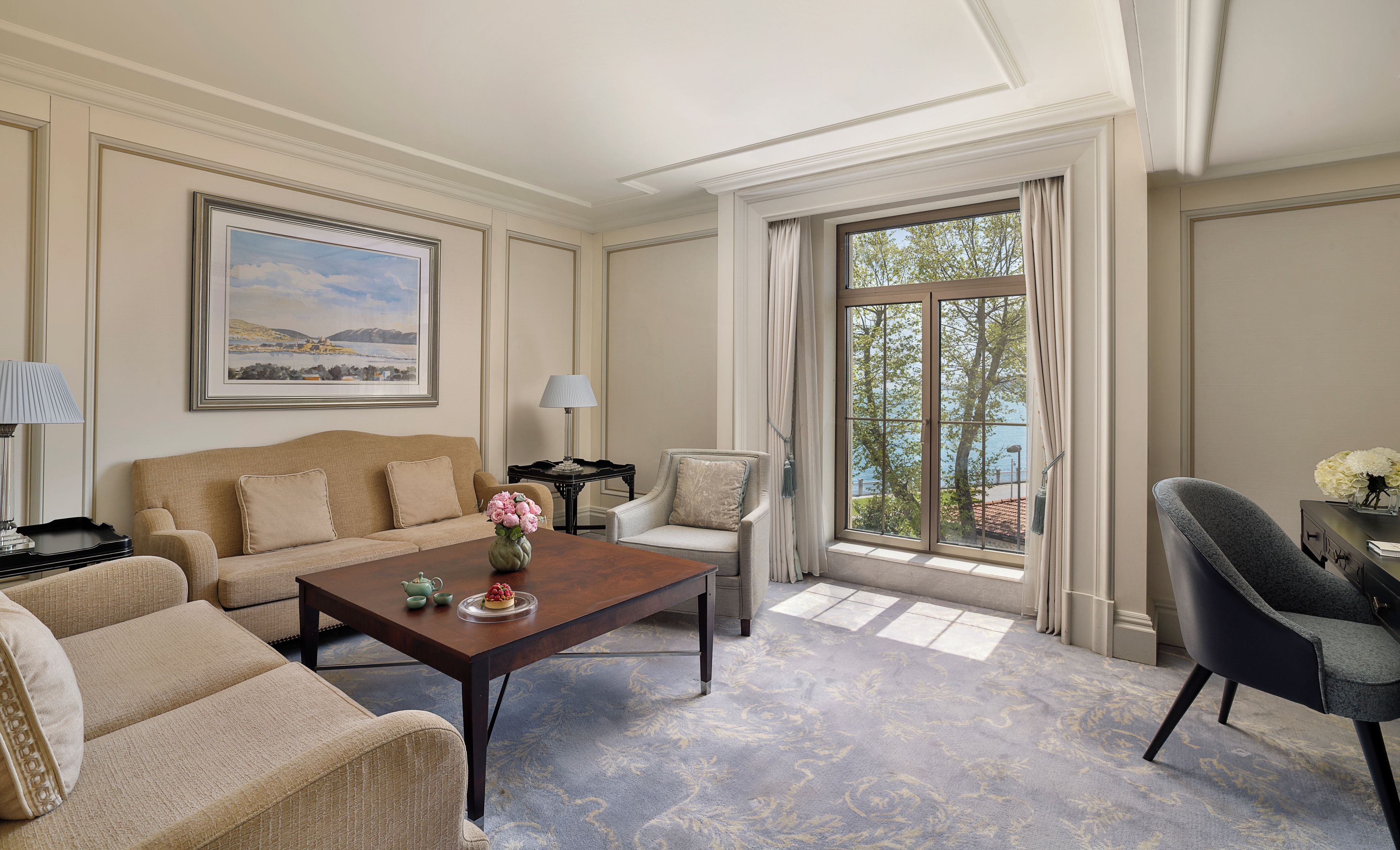 A well-appointed living room with a sofa, armchairs, a coffee table, and a view of the outdoors through large windows.
