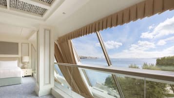 Habitación de hotel con un ventanal grande que ofrece vistas al mar, una cama bien hecha y un diseño moderno.