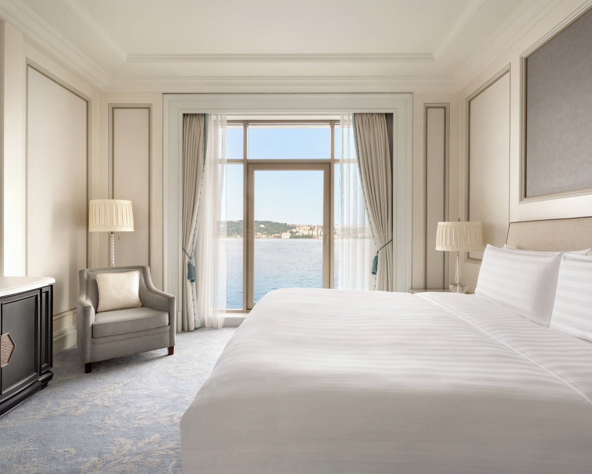 Une chambre d’hôtel avec un grand lit, une chaise, un bureau et une vue sur la mer.