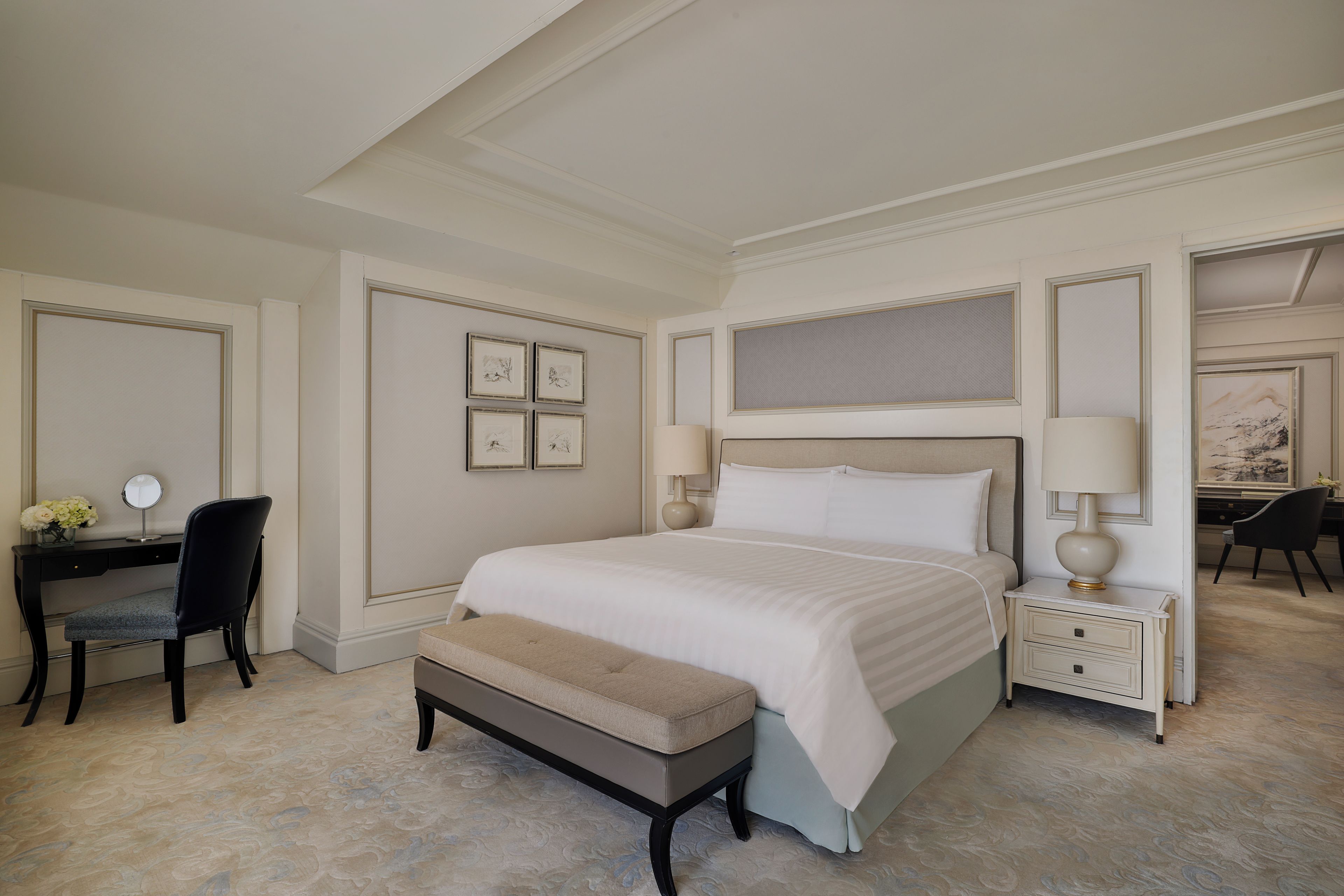 A neatly arranged bedroom with a bed, bedside tables, a desk, and a chair.