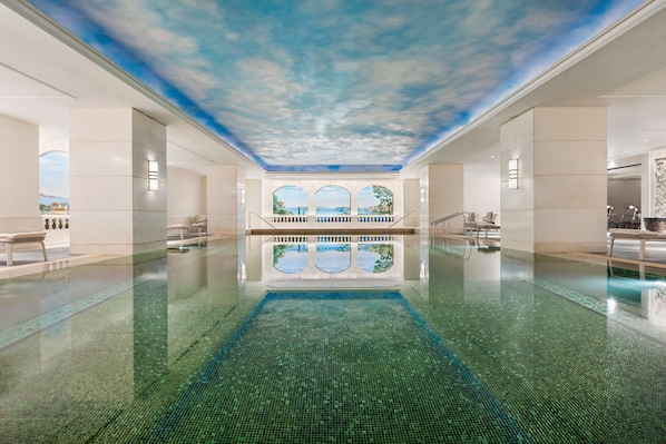 A large indoor swimming pool with a clear view of the sky through a ceiling mural, surrounded by white walls and a tiled floor. - Shangri-La Bosphorus, Istanbul (Istanbul)