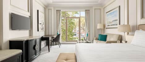Habitación de hotel con una cama grande, un escritorio, una silla, un televisor y una ventana con cortinas.