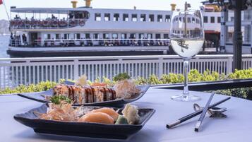 A dining table with a sushi dish, a glass of white wine, and chopsticks.