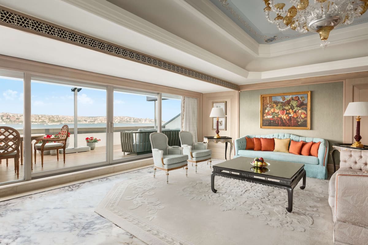 A spacious living room with a large window offering a city view, a plush sofa, a coffee table, and elegant chairs.
