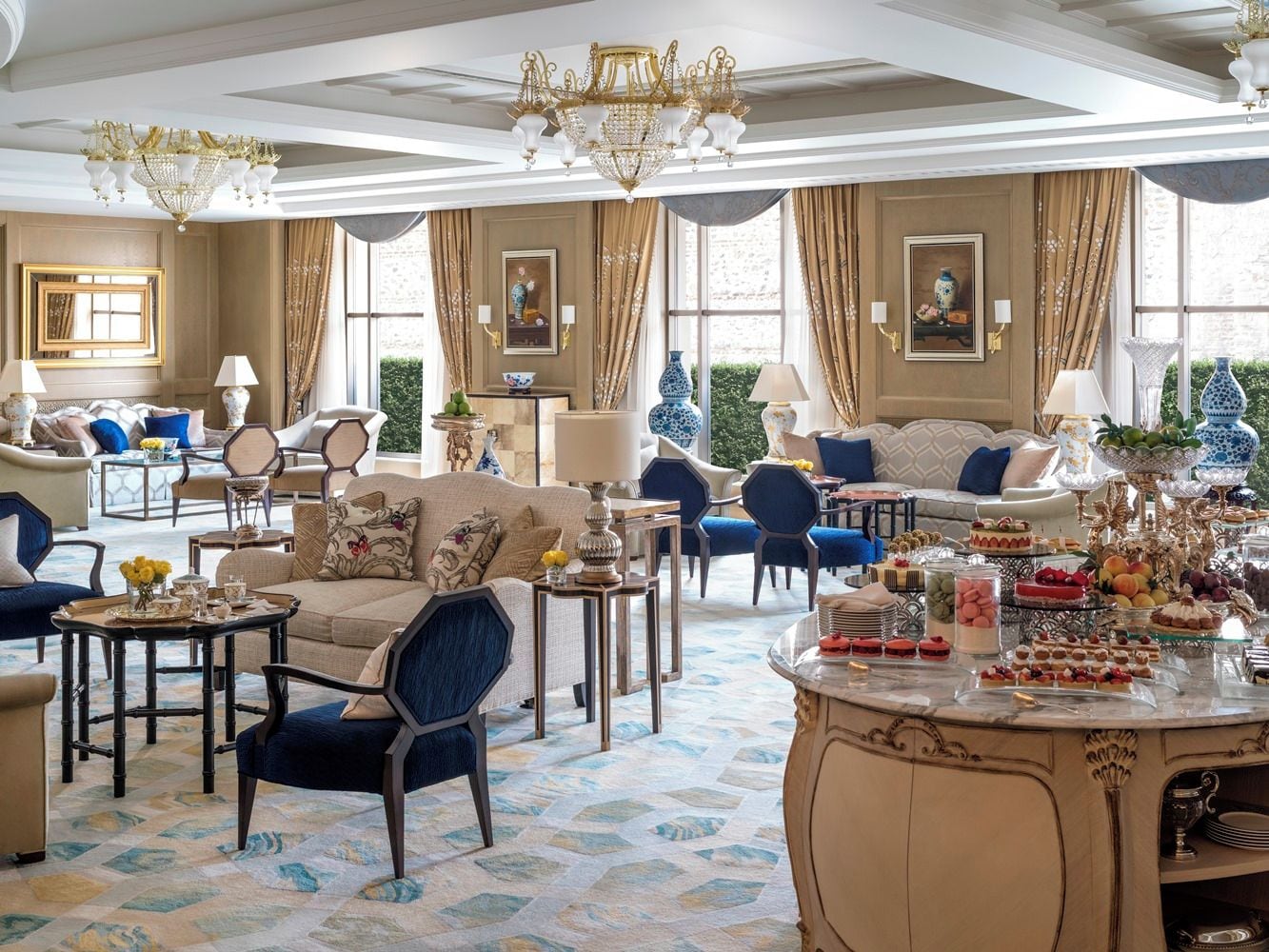 A luxurious hotel lobby with a seating area, a buffet table, and a chandelier.