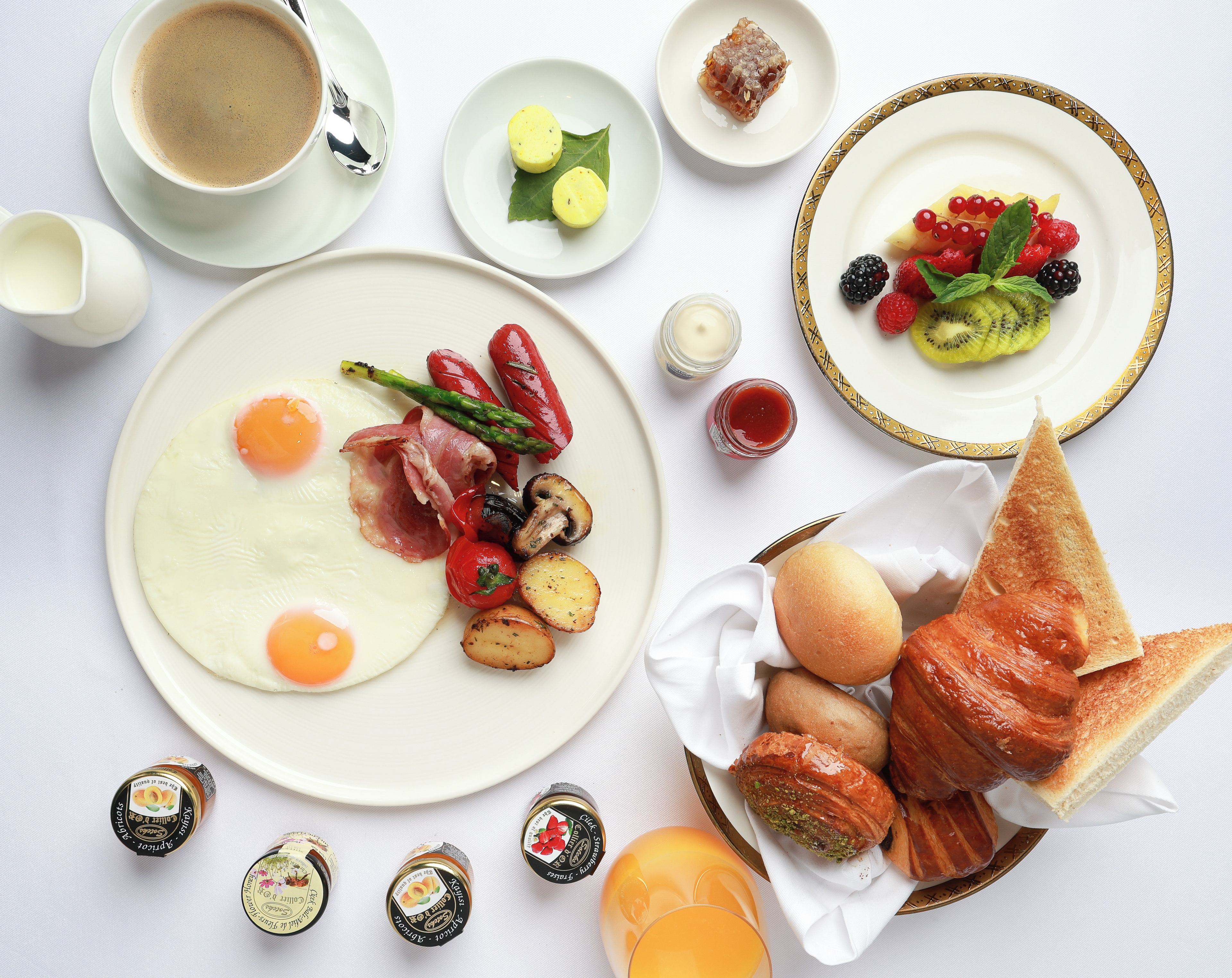 Une table mise pour le petit-déjeuner, avec des assiettes remplies de nourriture, une tasse de café et un panier de pain.