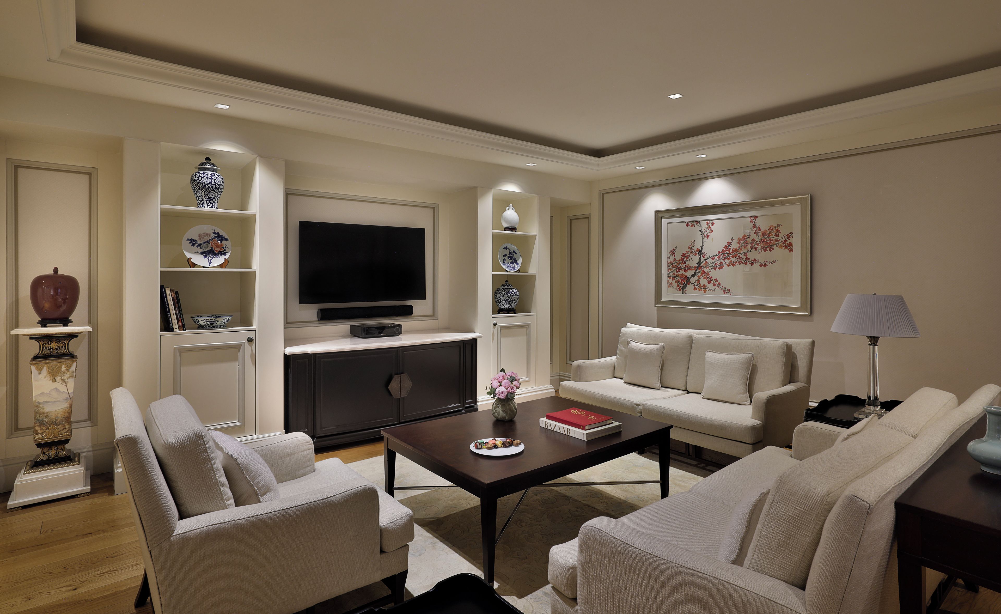 A modern living room with a flat-screen TV, sofas, a coffee table, and decorative items.