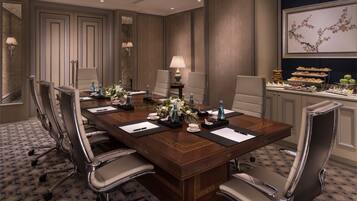 A conference room with a long table, chairs, and a buffet area with food and drinks.
