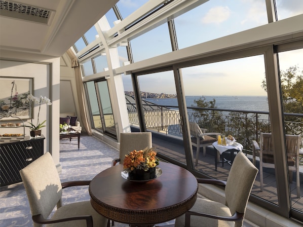 A balcony with a round table, chairs, and a vase of flowers.